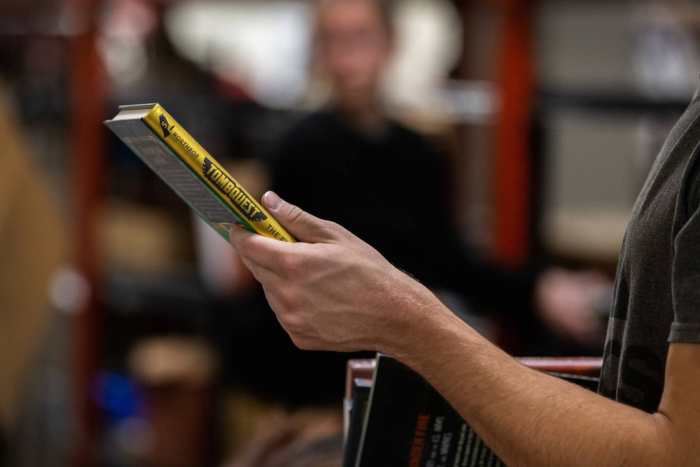 A Student holds a yellow-covered book titled "Tomb Raider" while browsing in a store.